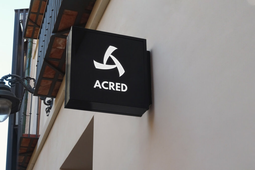 Logo ACRED sur un panneau de boutique en haut d'un mur.